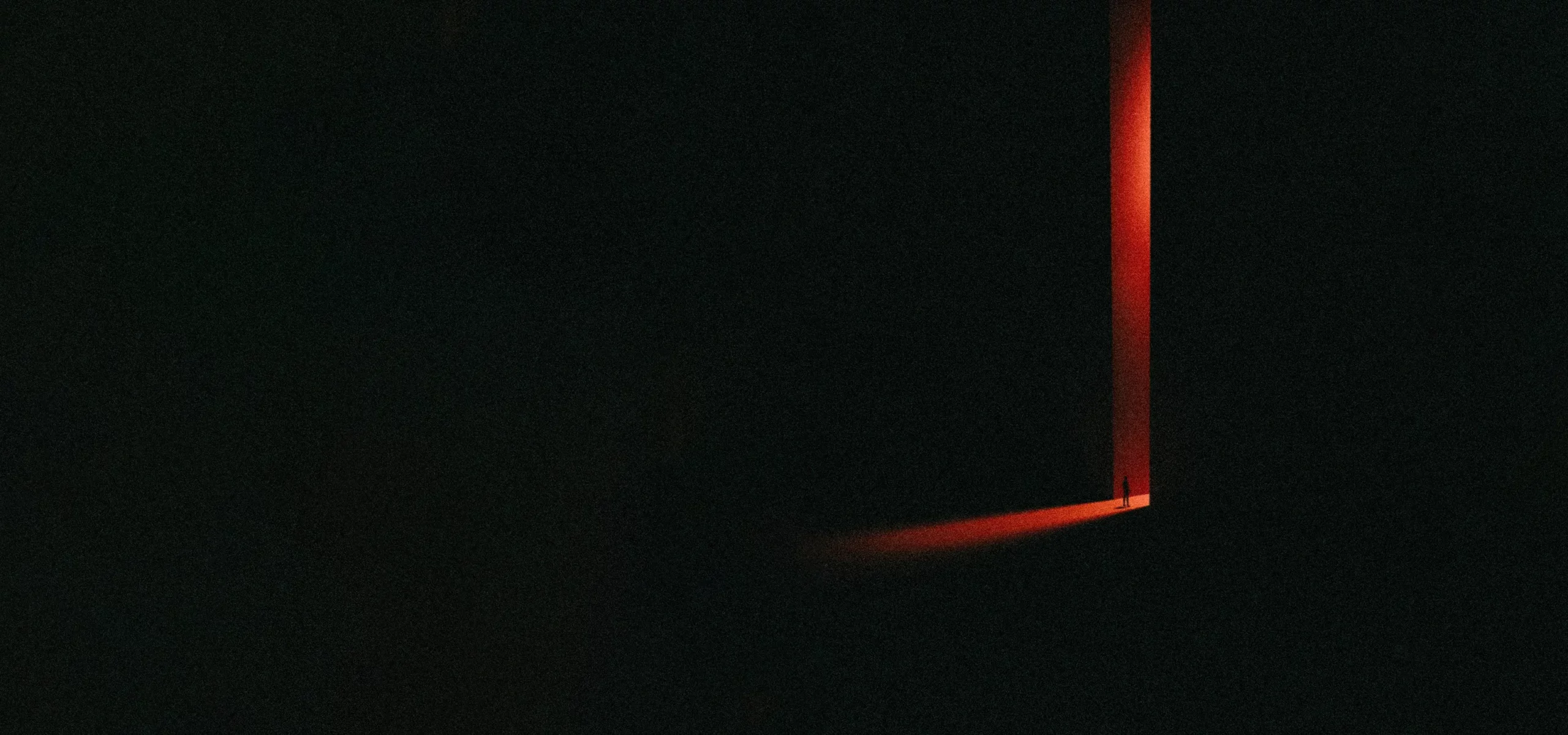 Dark doorway with a red beam of light, illustrating hidden aspects explored in shadow work