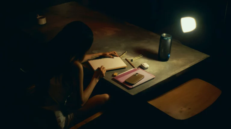 Person writing in a notebook at a dark table