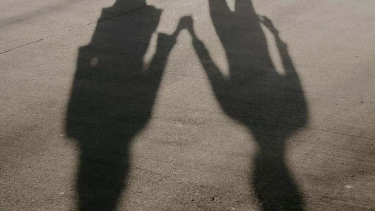 Shadows of two people holding hands on pavement