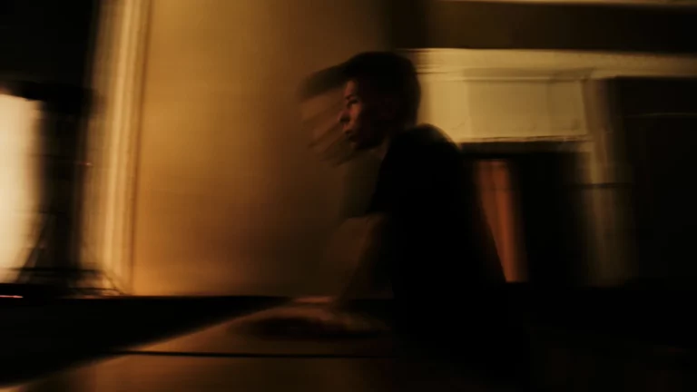 A blurred figure in amber light evoking memory and dream projection