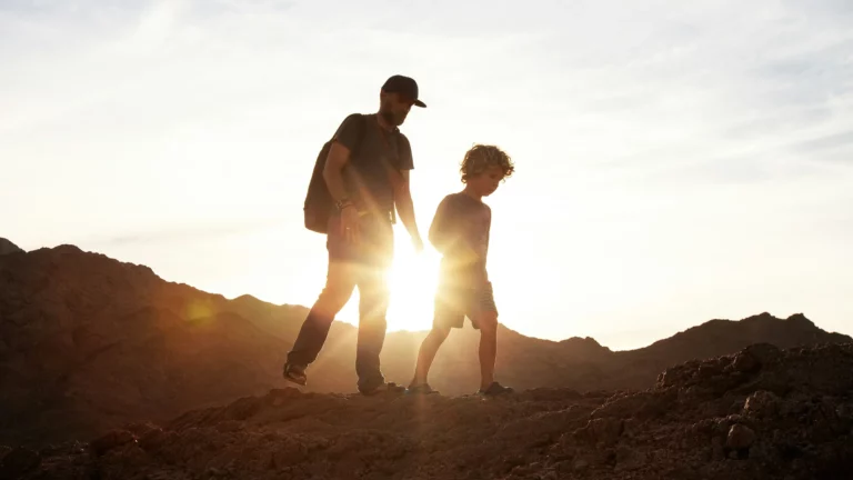 Father and child walking across a sunlit landscape