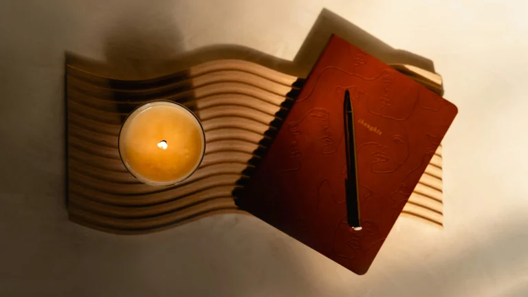 Notebook and candle arranged on a dark tabletop